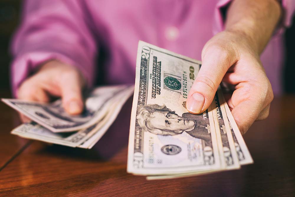 person hands money over in payment.