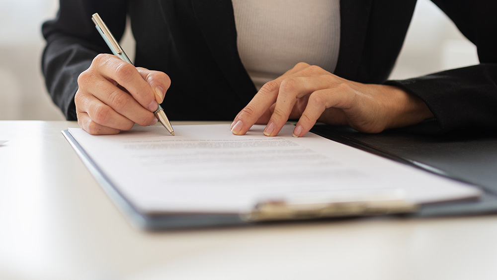 woman signing a document.
