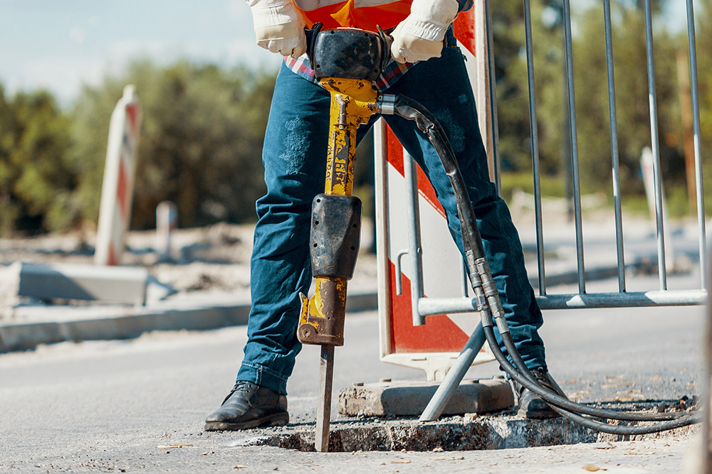 A worker uses a jackhammer to open up part of a street.