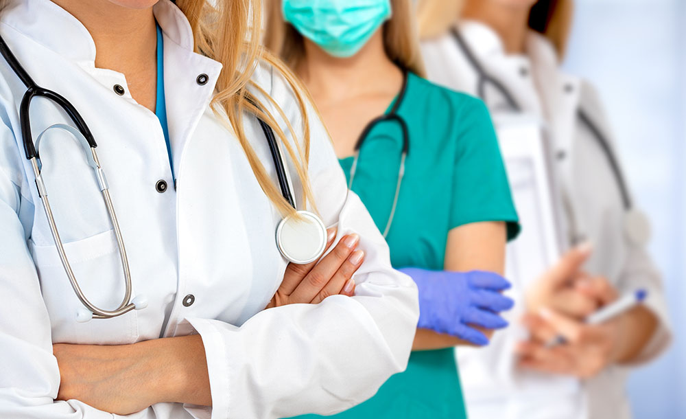 Three female doctors, nurses and physicians assistants standing in a line.