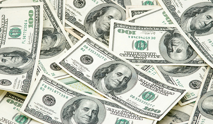 Promo image for the Taxes section of the website. Image of individual $100 bills scattered on top of each other in a pile.