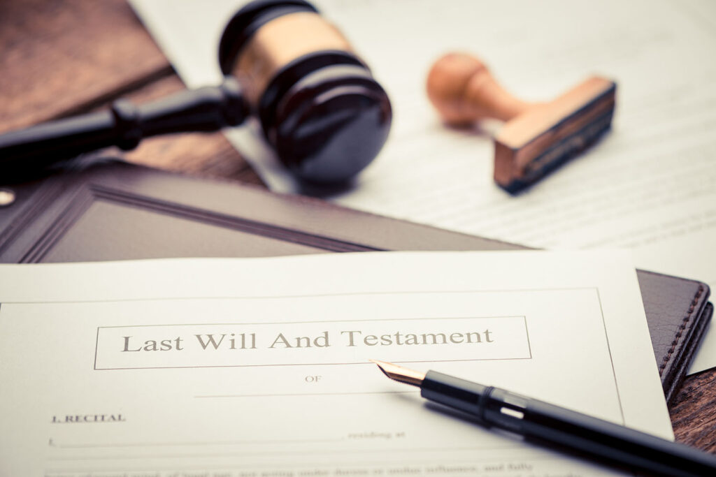 a last will and testament sits unsigned next to a fountain pen and a judicial gavel