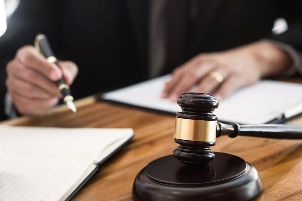 A Judge signs a document with a gavel in the foreground.